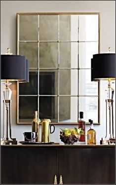 two lamps are sitting on top of a dresser in front of a mirror and other items