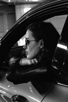 a woman sitting in the drivers seat of a car with her head out the window