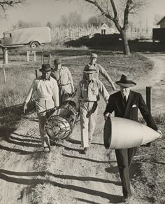 an old black and white photo of men walking down a dirt road with hats on