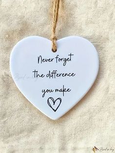 a white ceramic heart hanging on a rope with the words never forget the differences you make