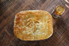 a piece of bread sitting on top of a wooden table next to a can of beer