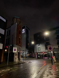 an empty city street at night with no cars on the road and buildings in the background