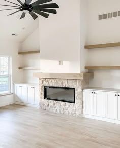 an empty living room with a fireplace and ceiling fan