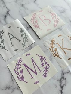 four napkins with different designs on them sitting on a marble counter top in front of the letter m