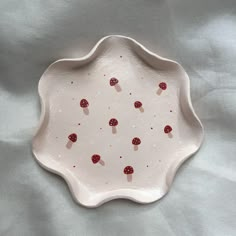 a white plate topped with red mushrooms on top of a tablecloth covered bed sheet