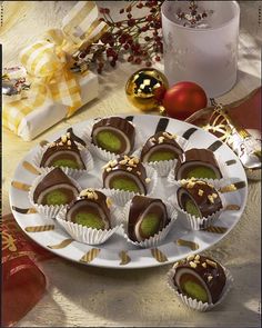 chocolate covered desserts on a white plate with christmas decorations and baubles in the background