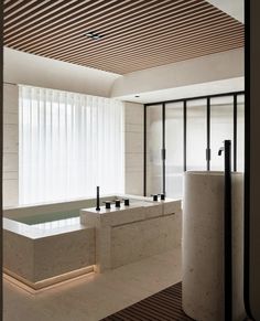 a large bath tub sitting next to a tall white pillar in a room with wooden slats on the ceiling