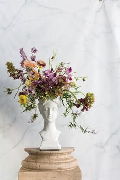 a vase with flowers in it sitting on top of a marble busturizer stand