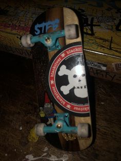 a skateboard with blue and white wheels sitting on top of a wooden floor next to graffiti covered walls