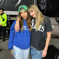 two young women standing next to each other in front of a stage with microphones