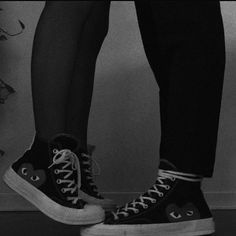 black and white photograph of someone's legs wearing high top converse sneakers with hearts on them