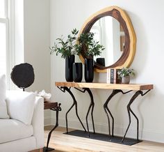 a living room with a white couch, mirror and plant in vases on the table