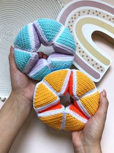 two crocheted doughnuts are being held by someone's hands next to it