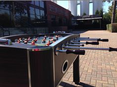 an outdoor foosball game set up in front of a brick walkway and building