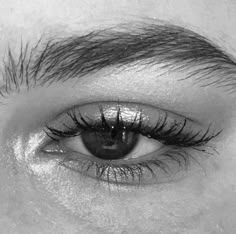 an eye with long lashes and no makeup is seen in this black and white photo