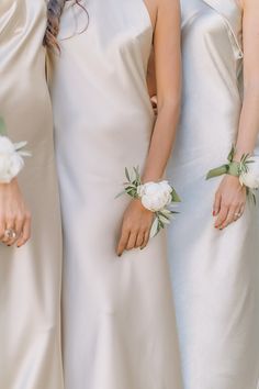 three bridesmaids in white gowns with flowers on their wrist ties and hair combs