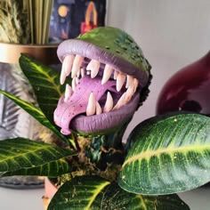 a fake dinosaur's mouth is on top of a plant with green leaves in the background