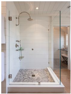 a walk in shower sitting next to a white towel on a rack and wooden floor