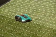 a robotic lawn mower sitting on top of a green grass covered field with white lines