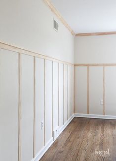 an empty room with white walls and wood paneling on the wall, along with hard wood flooring