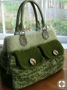 a green handbag sitting on top of a wooden table next to a large window