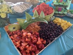 an assortment of fruits and vegetables are on display at a buffet table with blue cloth