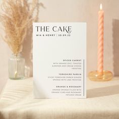 the cake menu sits on a table next to a candle