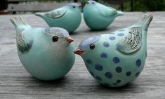 three blue ceramic birds sitting on top of a wooden table next to each other,