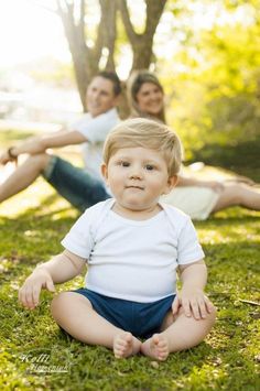 a young boy sitting on the grass with his mother