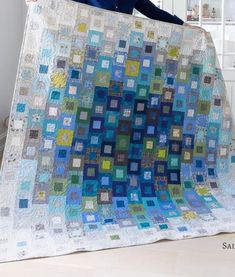 a woman standing next to a large quilt