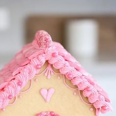 a close up of a gingerbread house with pink icing