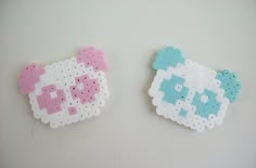 two hello kitty brooches sitting on top of a white table next to each other