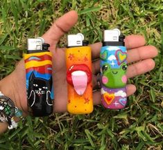 three different colored lighters in the palm of someone's hand, one with an open mouth