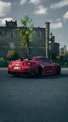 a red sports car parked in front of an old brick building with palm trees on the side