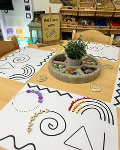 a wooden table topped with a potted plant on top of a white board covered in black and white designs