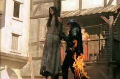 two people dressed in medieval clothing standing next to each other with fire coming from their hands