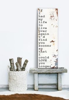 a wooden sign sitting next to a white basket filled with branches on top of a table