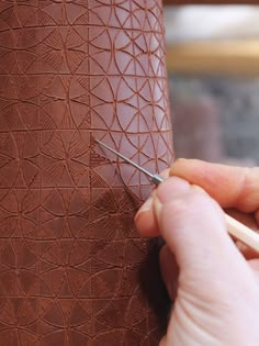 a person is cutting leather with a pair of scissors on the side of a vase