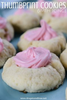 some cookies with pink frosting on them sitting on a blue plate and the words, thumpprint cookies with icing