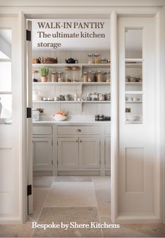 an open door leading to a kitchen filled with white cabinets and shelves full of utensils