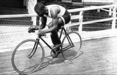 a man riding on the back of a bike down a wooden floor next to a fence