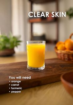 a glass filled with orange juice sitting on top of a wooden table