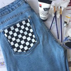 a pair of blue jeans with checkered pocket and paintbrushes on the side