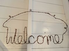 a sign that says welcome hanging on the side of a building with barbed wire around it