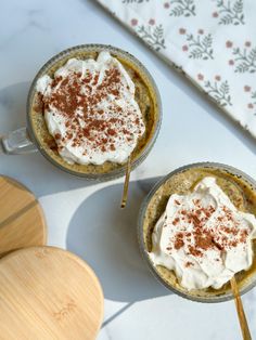 two cups filled with dessert sitting on top of a table next to wooden utensils