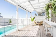 a wooden deck with chairs and tables next to a swimming pool