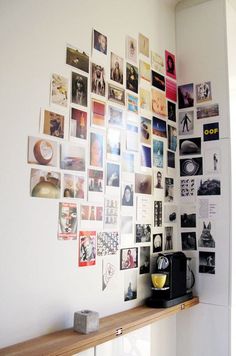 a white wall with many pictures on it and a wooden shelf in front of it