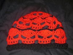 a crocheted hat with skulls on it sitting on top of a black blanket