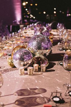 a table topped with lots of shiny disco balls and wine glasses on top of it