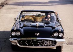 an old black car is parked on the side of the road